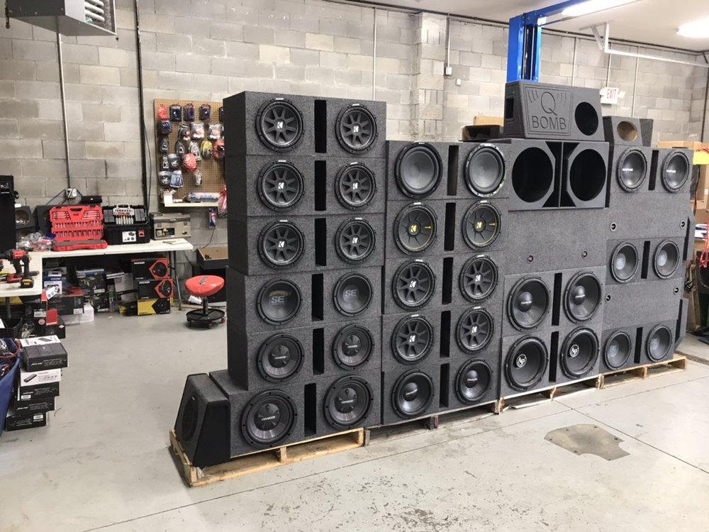 Wall of Kicker, Kenwood and Skar subwoofer enclosures at Shades Audio in Indianapolis